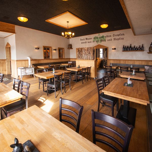 Restaurant mit Sitzgruppen und Spruch auf der Wand "Auch Wasser wird zum edlen Tropfen, mischt man es mit Malz und Hopfen"